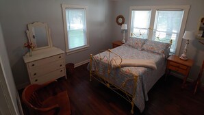 Quarto com cama, penteadeira, cadeira e duas mesas de cabeceira.