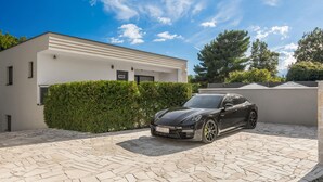 A modern house with a paved driveway and a black sports car parked in the driveway. - Stunning home in Labin (Labin)