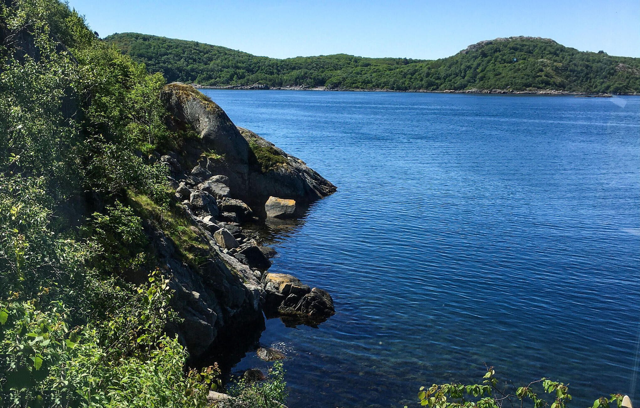 A coastal landscape with rocky cliffs and a clear blue sea.