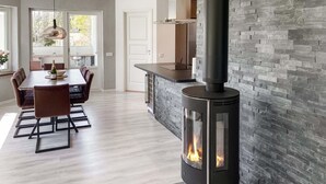 A modern kitchen with a stone wall, a built-in stove, and a dining area with a table and chairs. - 3 bedroom cozy home in Gotlands Tofta (Gotlands Tofta)