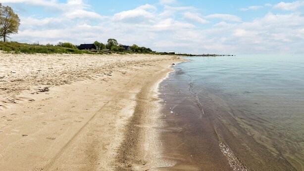 A beach with a clear sky, calm water, and a few houses in the background. - 3 bedroom cozy home in Gotlands Tofta (Gotlands Tofta)