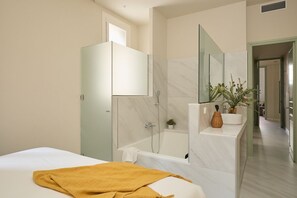 A modern bathroom with a bathtub, a glass shower enclosure, and a vanity with a mirror. - Casa Cosi - Don Bajos (Barcelona)
