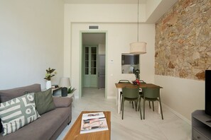 A modern living room with a sofa, coffee table, and dining area with chairs and a table.