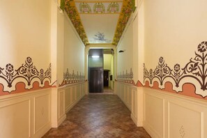 A hallway with ornate floral patterns on the walls and a tiled floor.