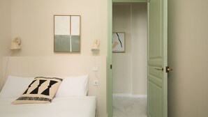 Een hotelkamer met een bed, nachtkastje, een wandlamp en een deur naar een badkamer.