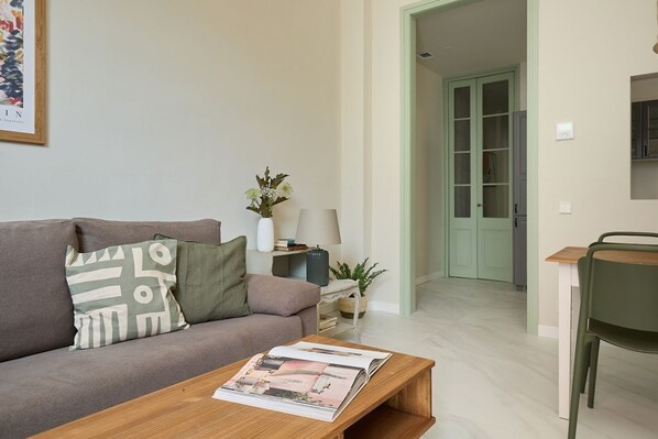 Una sala moderna con un sofá, una mesa de centro y una zona de comedor con una silla y una mesa.