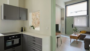 Een moderne keuken met grijze kastjes, een inbouwoven en een raam met uitzicht op een stadsbeeld.