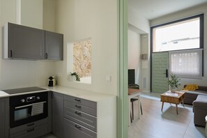A modern kitchen with grey cabinets, a built-in oven, and a window overlooking a cityscape. - Casa Cosi - Don Bajos (Barcelona)