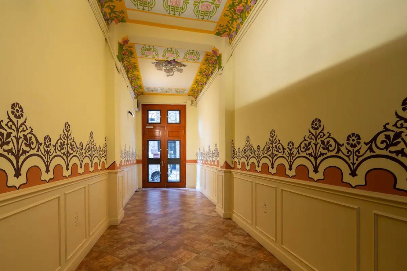 A hallway with ornate wall decorations and a wooden door at the end.