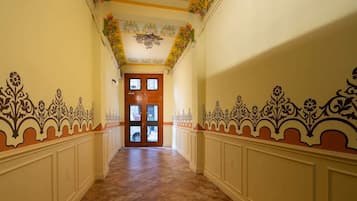 A hallway with ornate wall decorations and a wooden door at the end.