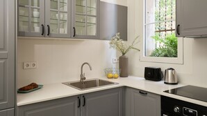 A modern kitchen with grey cabinets, a stainless steel sink, a toaster, and a kettle.