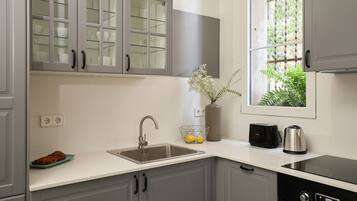 A modern kitchen with grey cabinets, a stainless steel sink, a toaster, and a kettle.