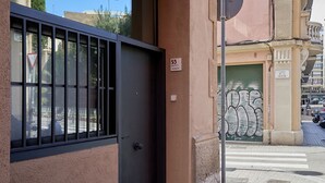 A building entrance with a black gate, a number 55 sign, and a green gate with a decorative design.