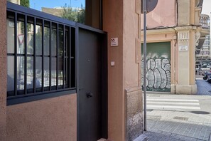 Une entrée d’immeuble avec un portail noir, une plaque portant le numéro 55, et un portail vert orné d’un motif décoratif.