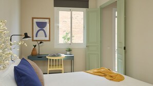 A bedroom with a bed, a desk, a chair, a window, and a door. - Casa Cosi - El Farro 4 (Barcelona)
