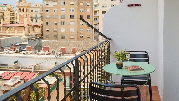 A balcony with a table and chairs, overlooking a cityscape with various buildings. - Casa Cosi - El Farro 4 (Barcelona)