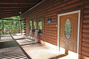 A wooden cabin with a porch, a welcome sign, and a door with a stained glass window.