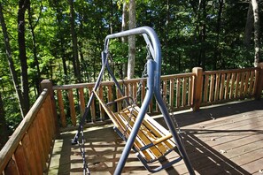 A wooden deck with a metal swing set. - Rocky View Lodge - Private Lodge in Hocking Hills (Laurelville)