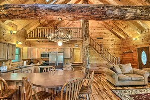 A spacious log cabin interior with a dining area, kitchen, and a cozy living space.