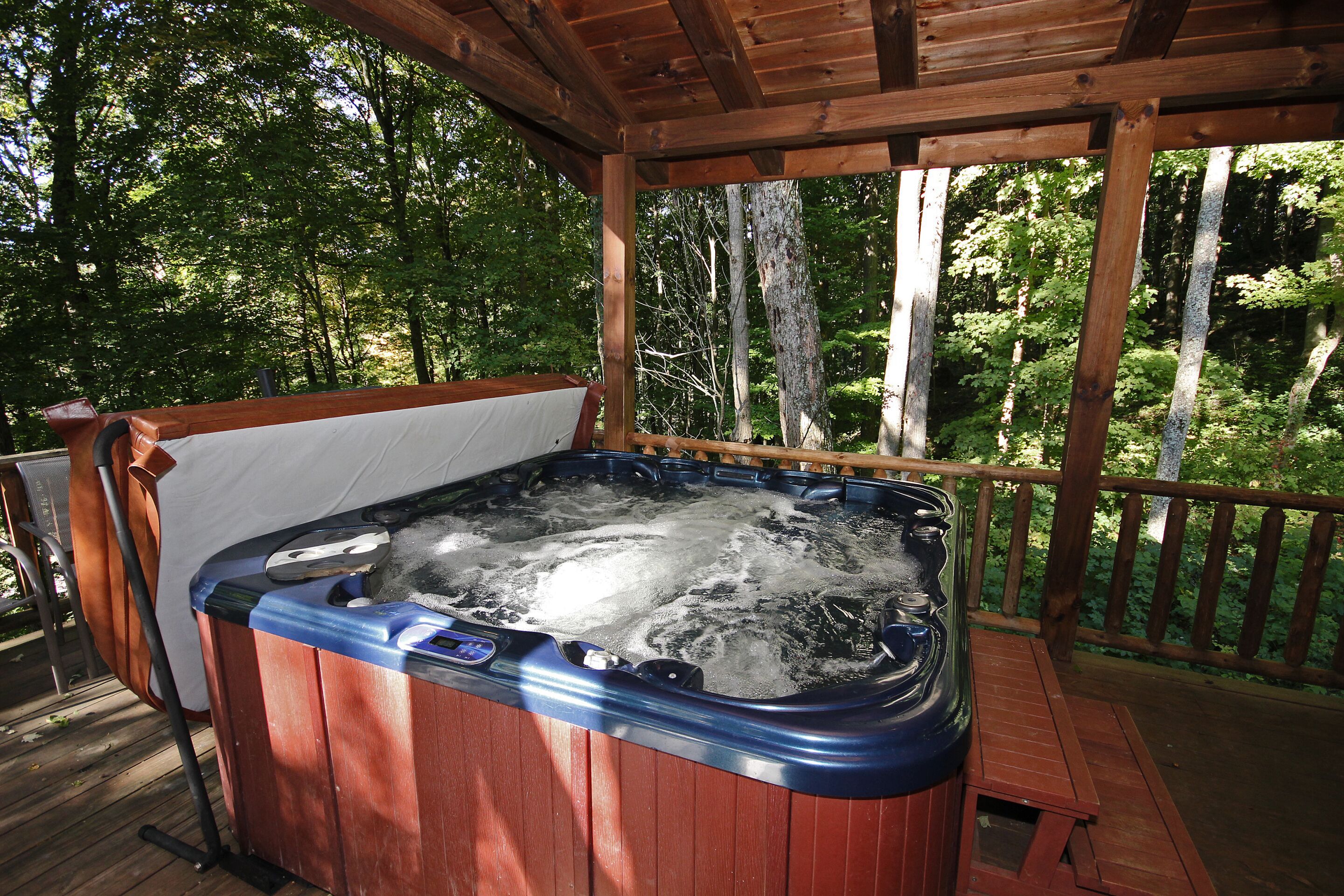A hot tub on a wooden deck with a view of a forest.