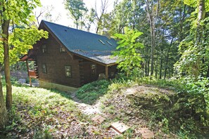 A rustic cabin with a sloped roof, surrounded by dense forest. - Rocky View Lodge - Private Lodge in Hocking Hills (Laurelville)