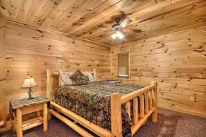 A wooden cabin bedroom with a bed, nightstand, lamp, and ceiling fan. - Rocky View Lodge - Private Lodge in Hocking Hills (Laurelville)