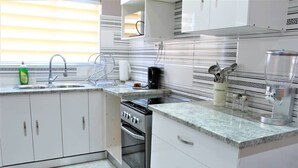 A modern kitchen with white cabinets, a stainless steel stove, and a granite countertop. - Escape Go Nest (Harare)