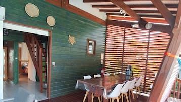 A wooden deck with a dining table and chairs, a staircase, and a green wall with decorative plates.
