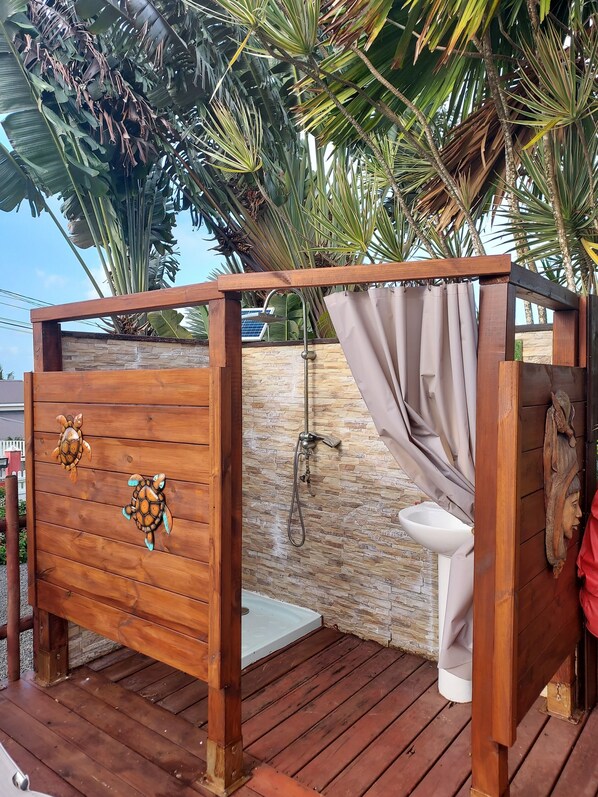 Eine Holzdar Terrasse mit einer Holzhütte, einem Duschbereich und einer Toilette.