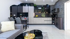 Une cuisine moderne avec des meubles de couleur sombre, un îlot central et un coin repas comprenant un canapé et une table basse.
