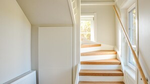 Una escalera con escalones de madera y paredes blancas.