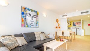 Ein modernes Wohnzimmer mit einem schwarzen Ledersofa, einem kleinen Holztisch und einem farbenfrohen, abstrakten Gemälde an der Wand.