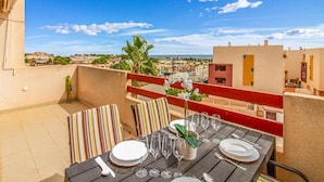 Ein Balkon mit Esstisch, Blick auf eine Stadtlandschaft mit Gebäuden und blauem Himmel.