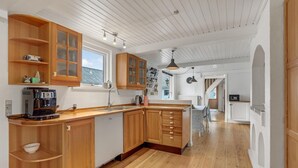 Una cocina con armarios de madera, una cafetera y un ventanal con vistas.