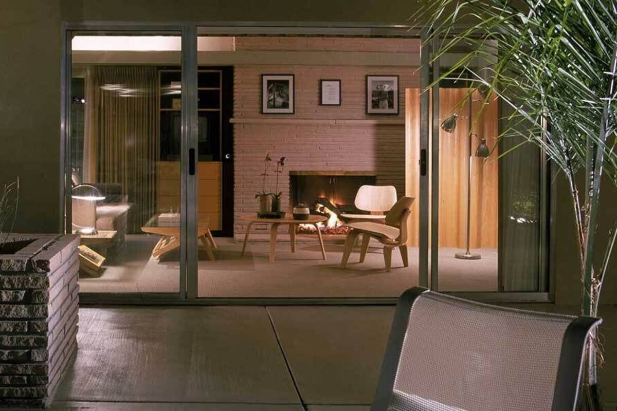 A modern living room with a fireplace, glass doors leading to another room, and a seating area with a table and chairs.