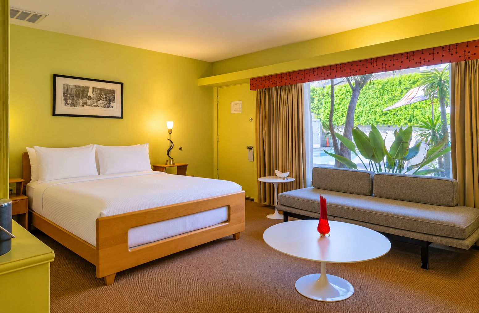 Een hotelkamer met een bed, een bank, een tafeltje en een raam met gordijnen.