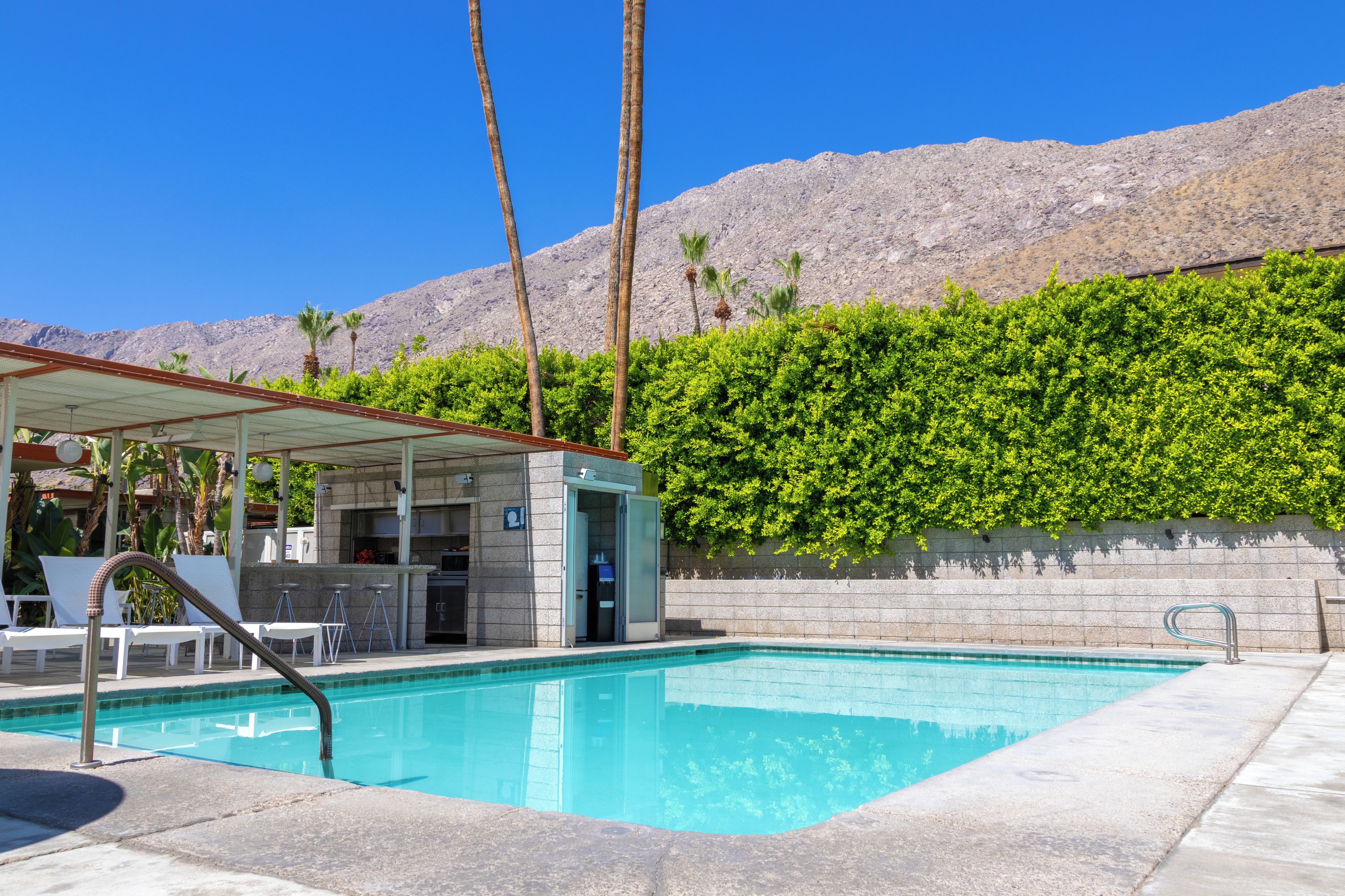A pool area with a bar, lounge chairs, and a mountain backdrop.