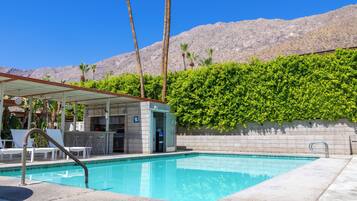 A pool area with a bar, lounge chairs, and a mountain backdrop.