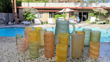 Un área de piscina con sillones de descanso, sombrillas y una jarra decorativa.