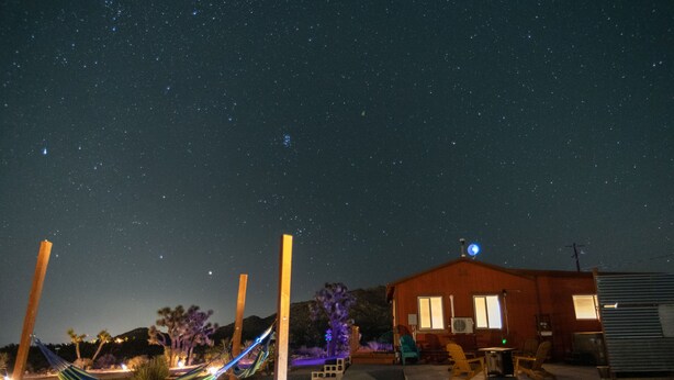 A starry night sky, a hammock, a small house with a satellite dish, and a desert landscape.