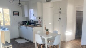A modern kitchen with white cabinets, a dining table with chairs, and a wooden floor.
