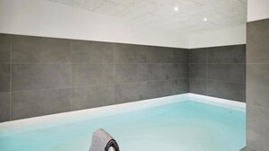 A modern indoor swimming pool with grey tiled walls and a white ceiling. - Stunning home in Blokhus with kitchen (Blokhus)