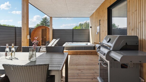 An outdoor patio with a hot tub, a grill, wicker furniture, and a wooden deck. - Stunning home in Blokhus with kitchen (Blokhus)