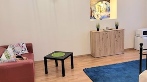 A modern living room with a red sofa, a wooden cabinet, a small black table, and a blue rug.