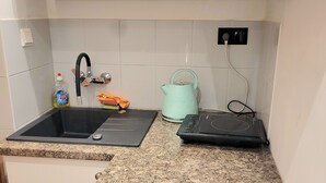 A kitchen with a granite countertop, a black sink, a teal kettle, and a black portable heater.