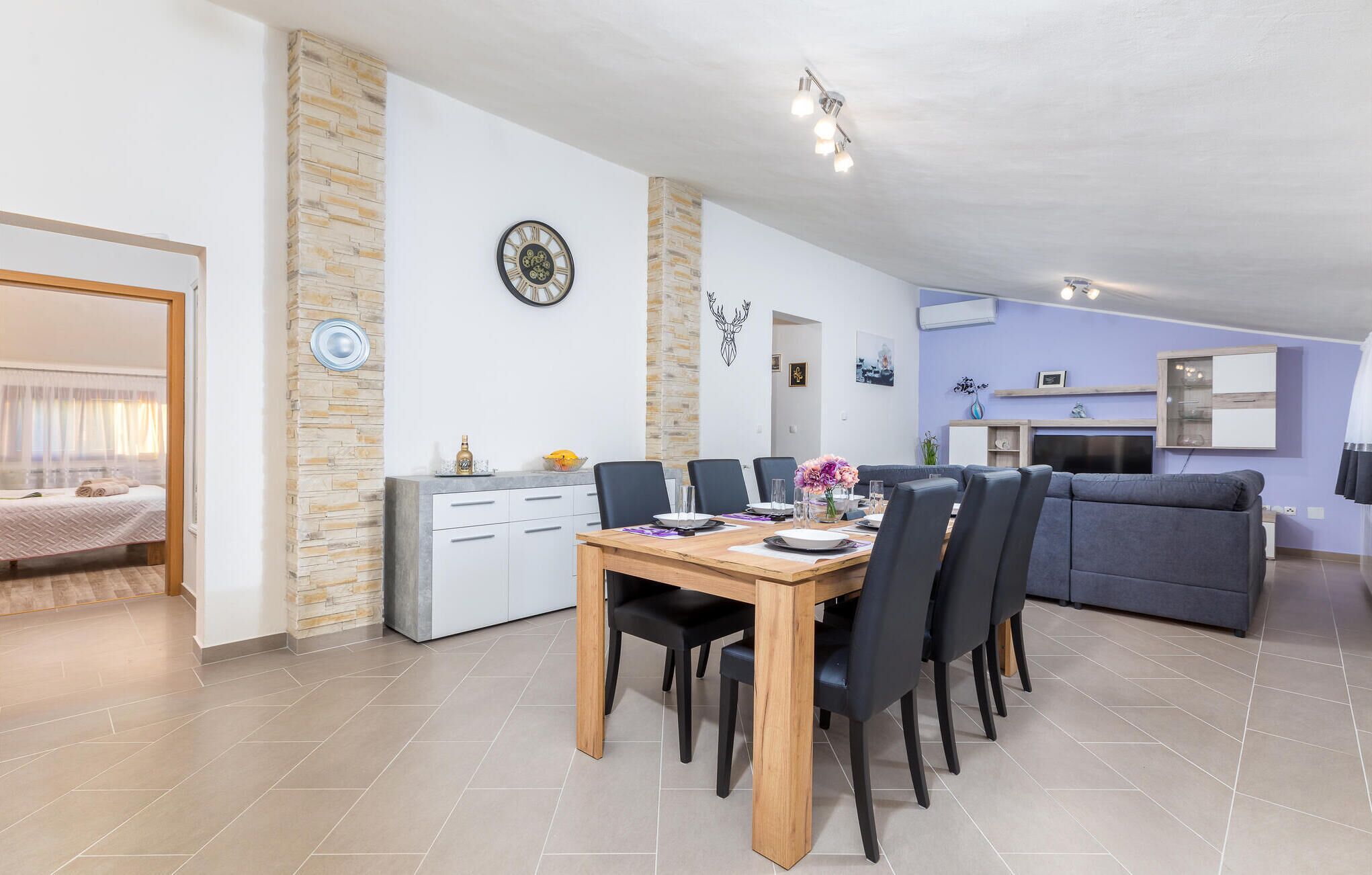 Een moderne woonkamer met een eethoek, een bank, een open haard en een keuken.