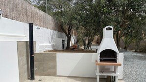 Un patio con una griglia fissa e un piccolo tavolo di legno.
