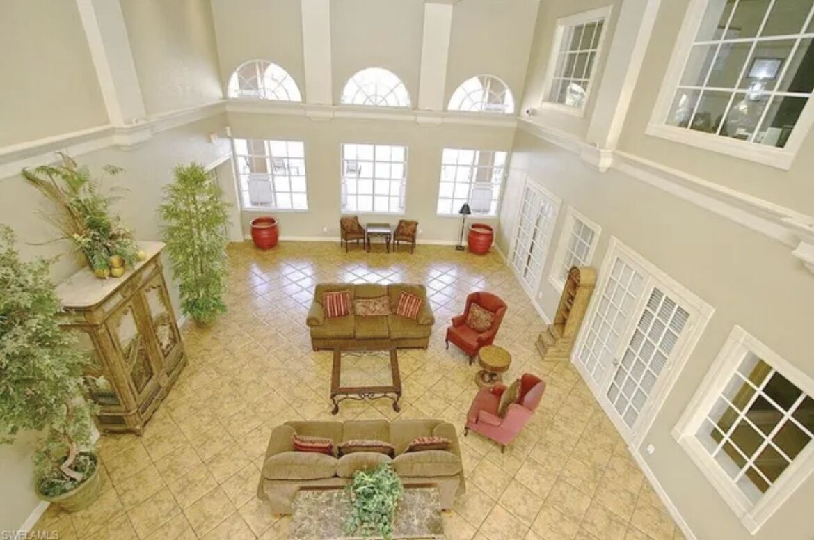 Un intérieur spacieux avec un plafond haut, de grandes fenêtres et un espace salon central agrémenté de canapés et de fauteuils.