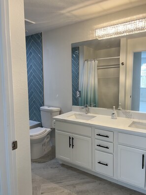 A bathroom with a white vanity, a large mirror, and a shower area. - GORGEOUS TOTALLY RENOVATED 3BED,2BATH CONDO IN GREAT COMMUNITY!!! (Naples)