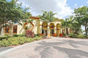 A building with a yellow facade, arched windows, and palm trees in the foreground. - GORGEOUS TOTALLY RENOVATED 3BED,2BATH CONDO IN GREAT COMMUNITY!!! (Naples)